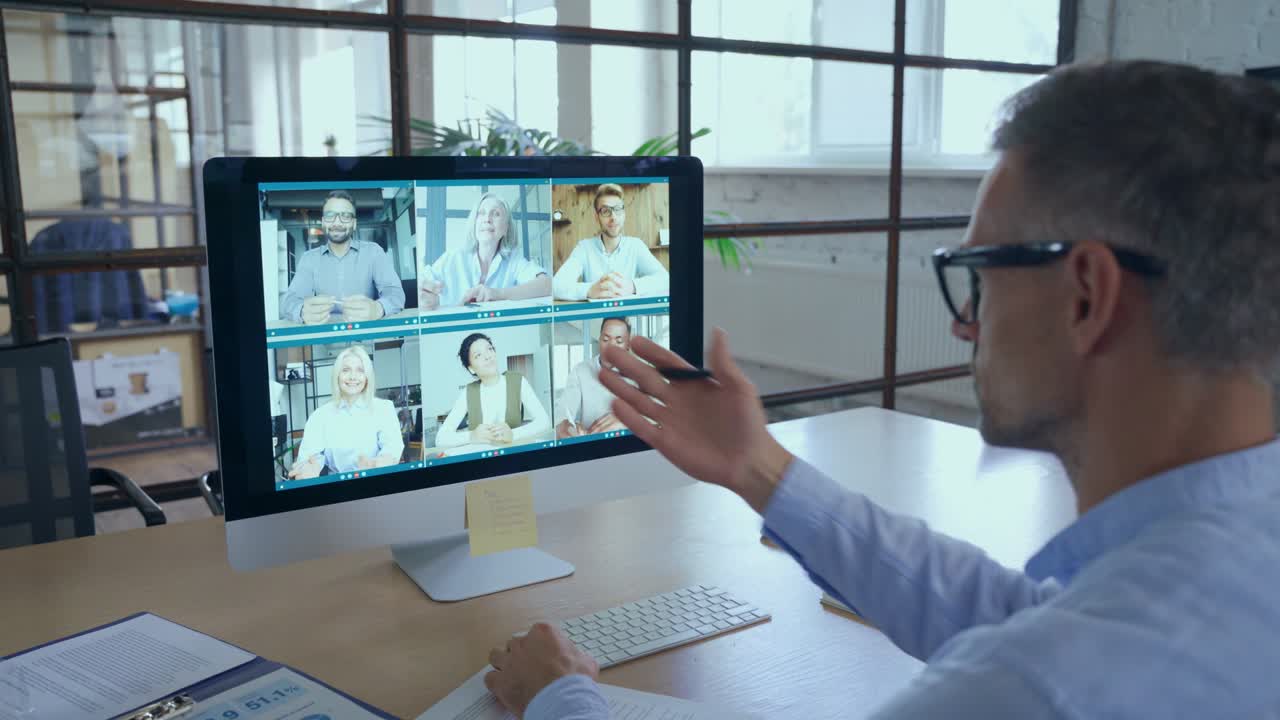 Businessman talking with team leading virtual meeting on computer. Over shoulder