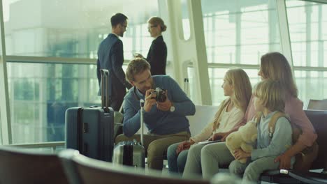 hombre tomando fotos con una cámara fotográfica de su bella esposa e hijos en la sala de salidas del aeropuerto