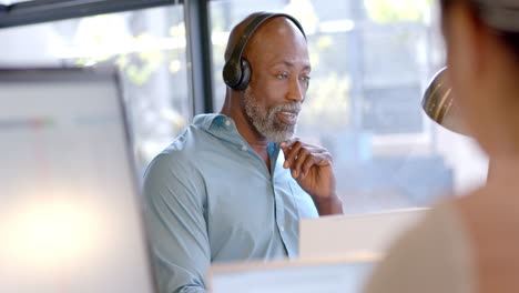 african american businessman using headphones in office with copy space