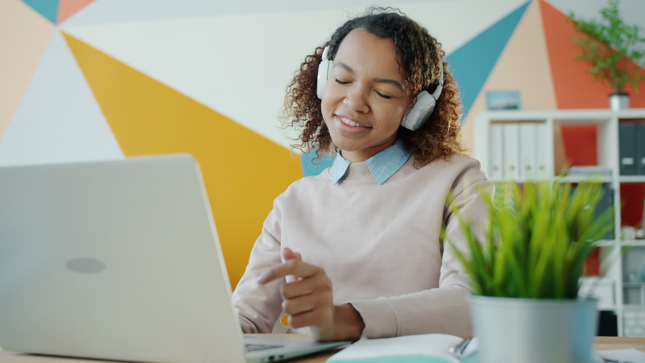 Happy Woman Enjoying Music While Working on Laptop