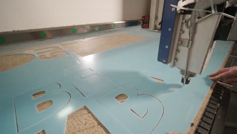 máquina de corte cnc en el trabajo, corte de hojas de plástico acrílico. producción de carteles publicitarios