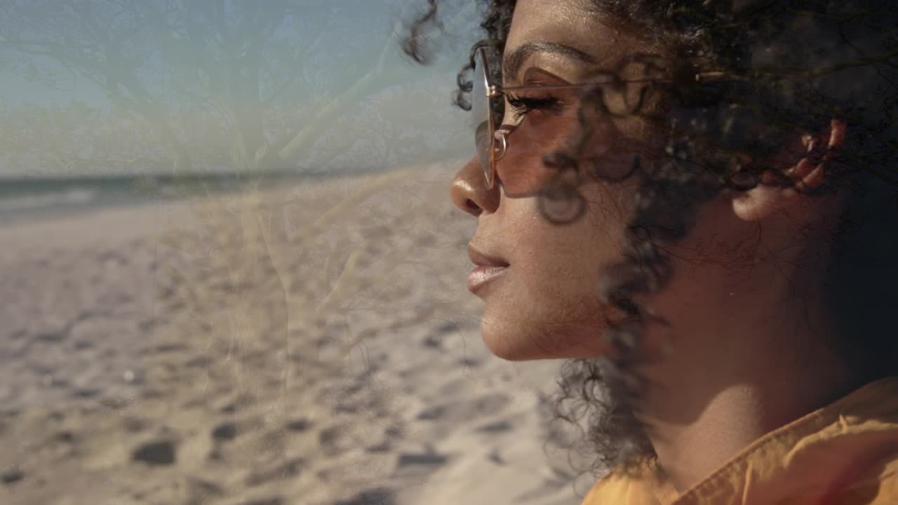 Animation of tree over african american woman at beach smiling