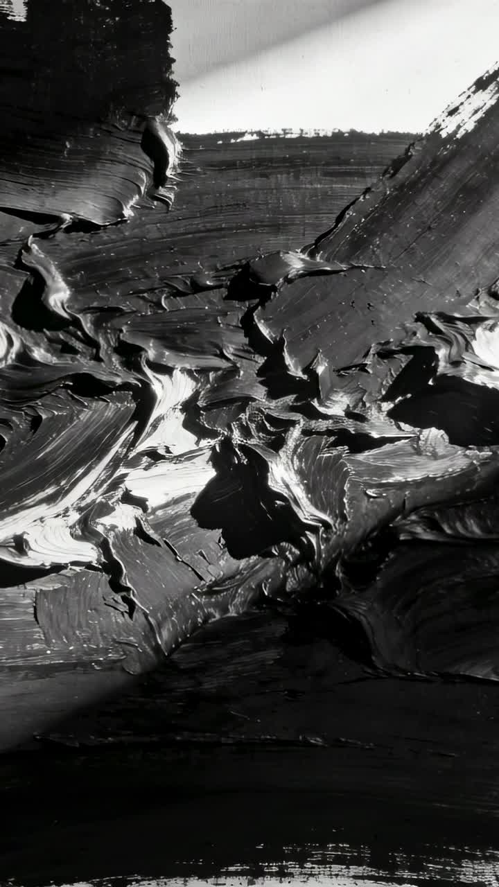 Vidéo verticale : Caméra mobile révélant les détails de peinture en empâtement en studio, montrant d'épaisses crêtes sombres