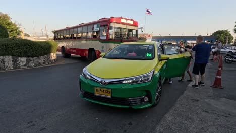 green taxi and red bus at a busy transport hub