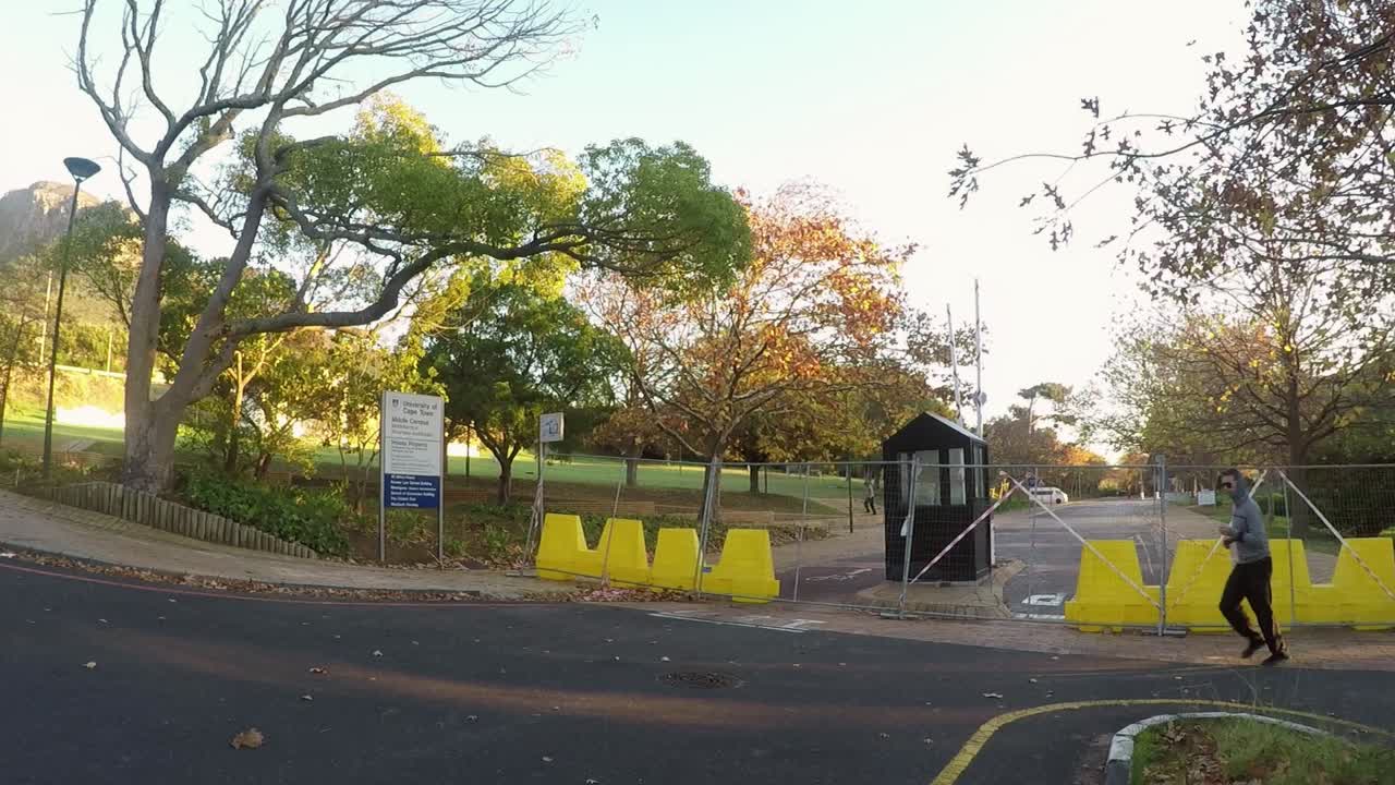 University of Cape Town middle campus road closed with yellow barriers and wire fencing. Runner exercising on property during Covid-19 National Lockdown. UCT is located below Devils Peak.