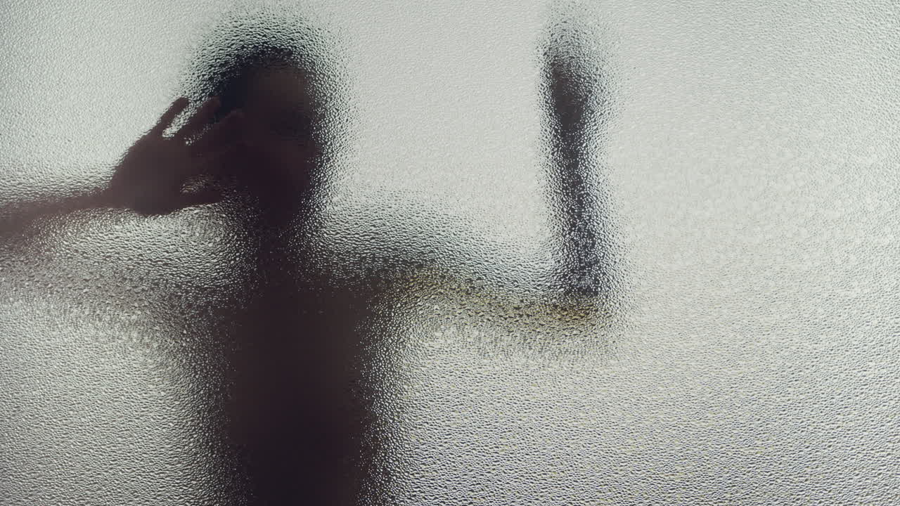 A female silhouette behind the frosted window dances slowly