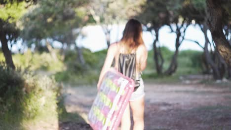 young teenage boy wraped in beach towel and youg teenage girl in swimsuit and shorts with pink inflatable float walking in 
mediterranean vegetation by the sea in the evening