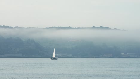 sailing boats middle of blue river in foggy scene, lisbon city, portugal