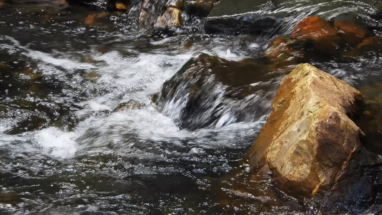 Acqua cristallina e fresca di cascata montana e del fiume Crocodile, scintillante e che scorre su rocce e ciottoli, nei giardini botanici nazionali Walter Sisulu a Roodepoort, Sudafrica