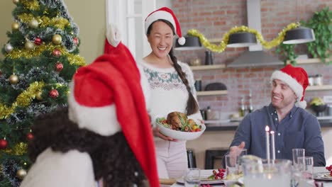 Feliz-Grupo-De-Amigos-Diversos-Con-Gorros-De-Papá-Noel-Celebrando-La-Comida-En-Navidad