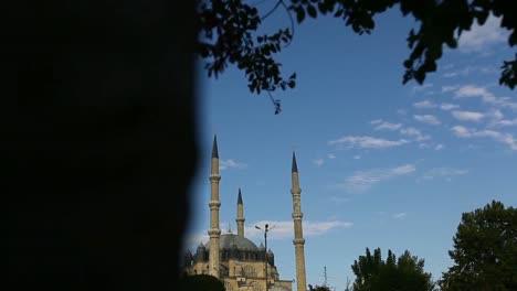 Sultan-Selim-Mosque-in-Konya,-Turkey-and-beautiful-colorful-flowers-and-many-people-and-tourists-with-blue-and-cloudy-sky