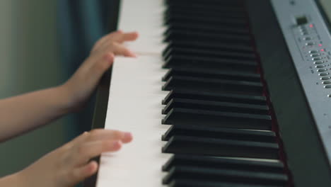 little child plays music synthesizer pressing keys in room