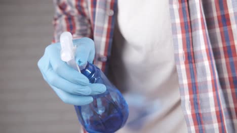 person cleaning with spray bottle and gloves