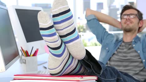 Photo-editor-smiling-with-his-feet-up-on-his-desk