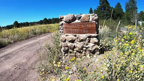 pan from a private road marked by a stone and wood sign to dirt road