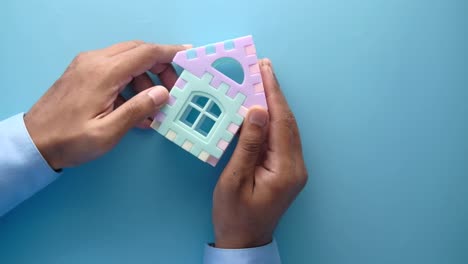 manos sosteniendo una colorida casa de juguetes