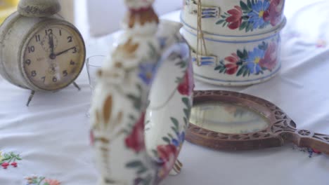 reloj antiguo, jarra de agua, tazas con diseño floral en la mesa