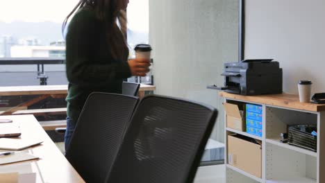 Front-view-of-young-Asian-businesswoman-walking-with-coffee-cup-in-modern-office-4k