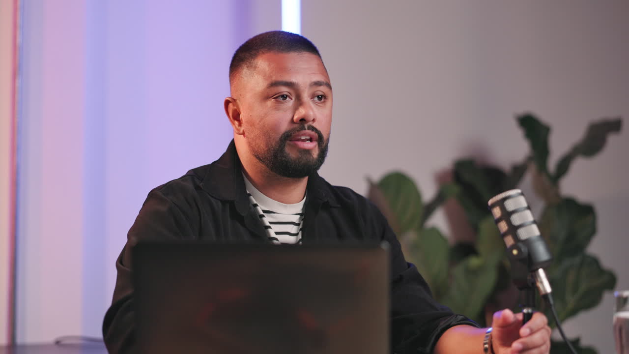 Man recording a podcast with a microphone and laptop