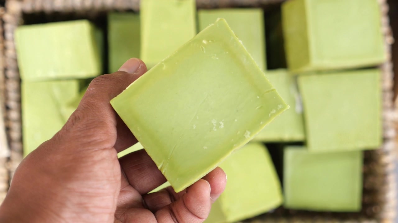 Primo piano di una mano che tiene una saponetta naturale verde