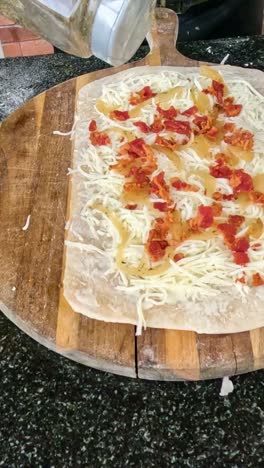 añadiendo ingredientes a la masa de pizza en una tabla de madera