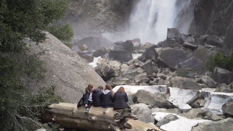 slow motion shot of four college age girls sitting on a log looking at a waterfall in yosemite national park