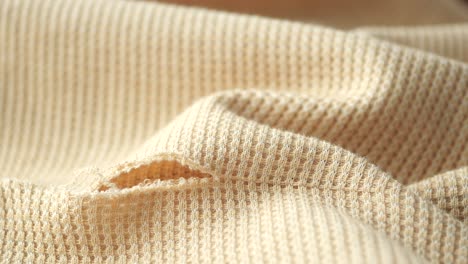 close-up of a torn piece of beige waffle knit fabric