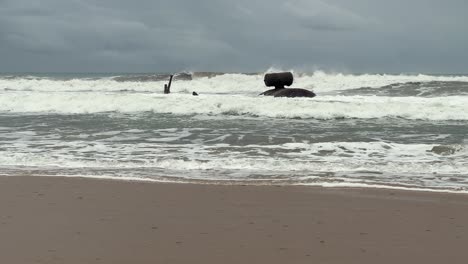 en la costa española, las olas chocan contra la costa bajo un telón de fondo de clima nublado y temperamental, retratando la eterna danza del mar y la naturaleza.
