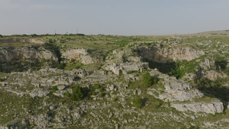 Aerial-flyover-of-the-canyon-and-caves-opposite-the-town-of-Matera-in-Italy-during-the-light-of-the-sunset