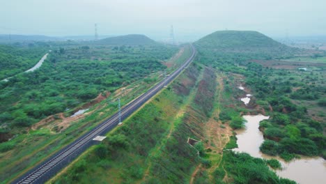 Aerial-Drone-shot-of-Railway-Track-with-green-hillly-landscape-in-North-India