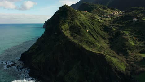 Paraglider-travels-past-iconic-green-cliffs-of-Madeira-at-coast,-aerial