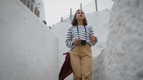 Girl-walk-white-street-in-old-city-vacation.-Vertical-travel-blogger-make-photos