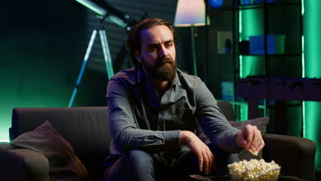 man enjoying bowl of popcorn and smiling while watching cable programs on tv