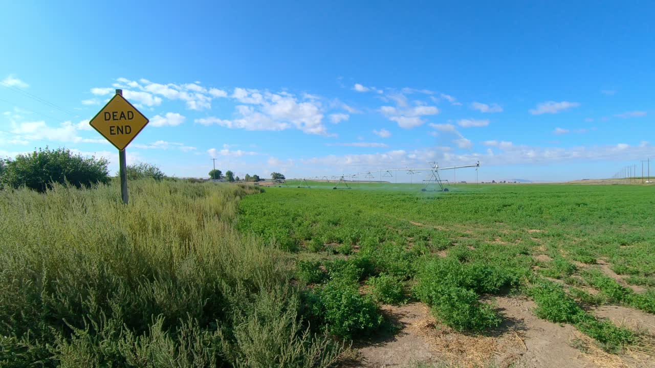 Pan  view of Pivot Irrigation system on an alfalfa field in eastern Washington state; as camera pans to the edge of the field a Dead End sign is visible