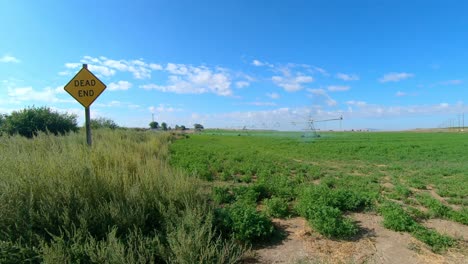 pan  view of pivot irrigation system on an alfalfa field in eastern washington state; as camera pans to the edge of the field a dead end sign is visible