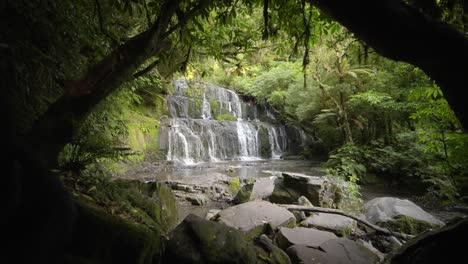 Waterfall-amongst-an-idyllic-forest-with-green-trees-everywhere,-wide-shot