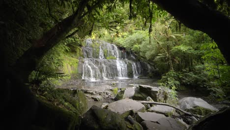 waterfall amongst an idyllic forest with green trees everywhere, wide shot