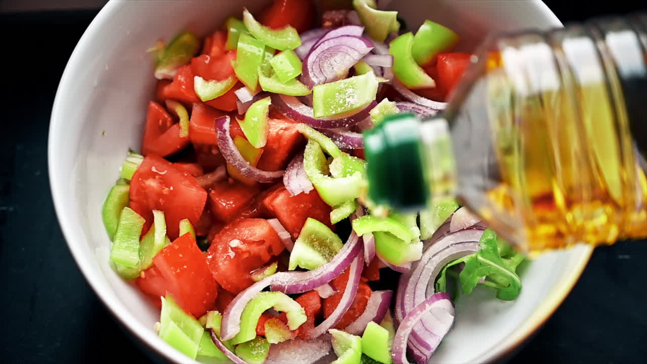 A man is dressing a healthy salad with olive oil. Slow motion
