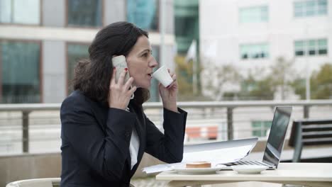 businesswoman talking by smartphone and drinking coffee