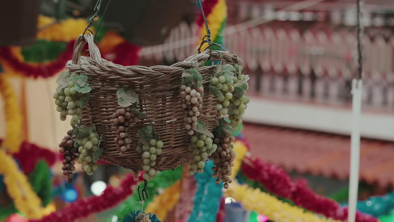 Cesto di vimini con decorazioni a forma di grappolo d'uva appeso in un interno festivo