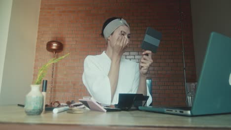 woman applying makeup while video calling