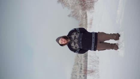 A-Man-Standing-Amidst-Deep-Snow,-Joined-by-His-Dog---Vertical-Shot