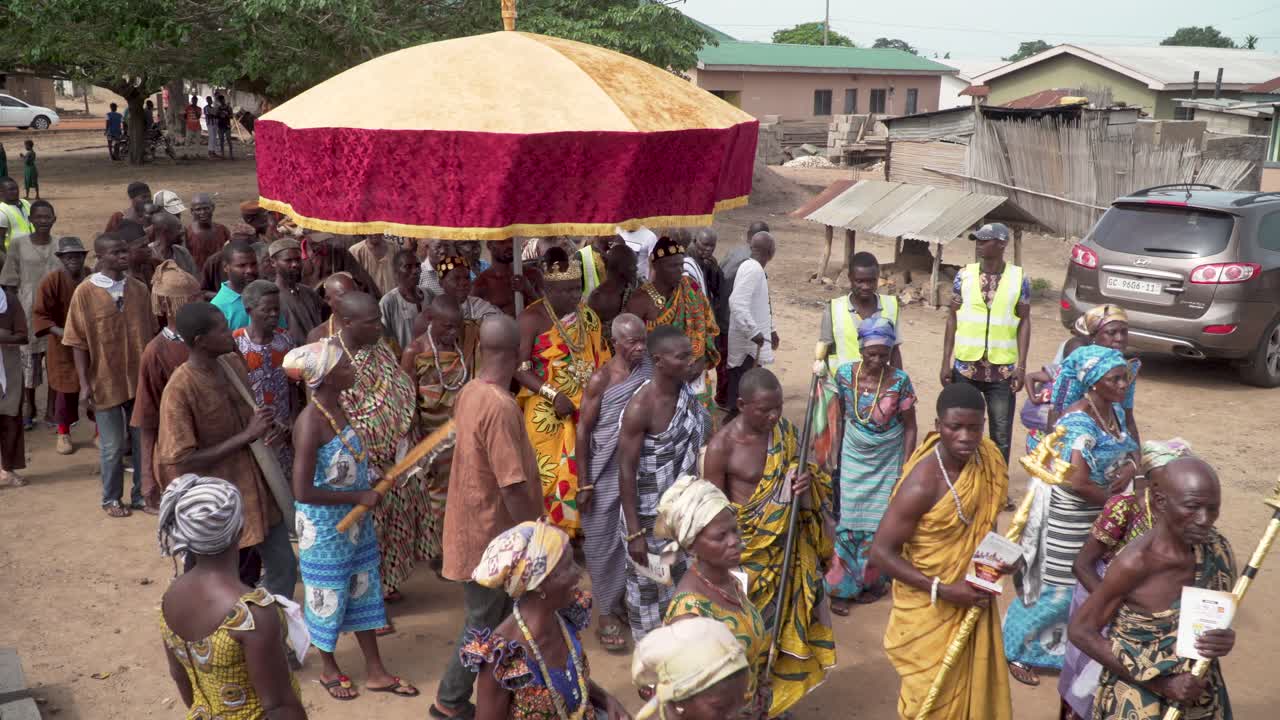 As part of a village festival the paramount chief marches under a royal umbrella with his aids to the village square in rural Ghana, West Africa.