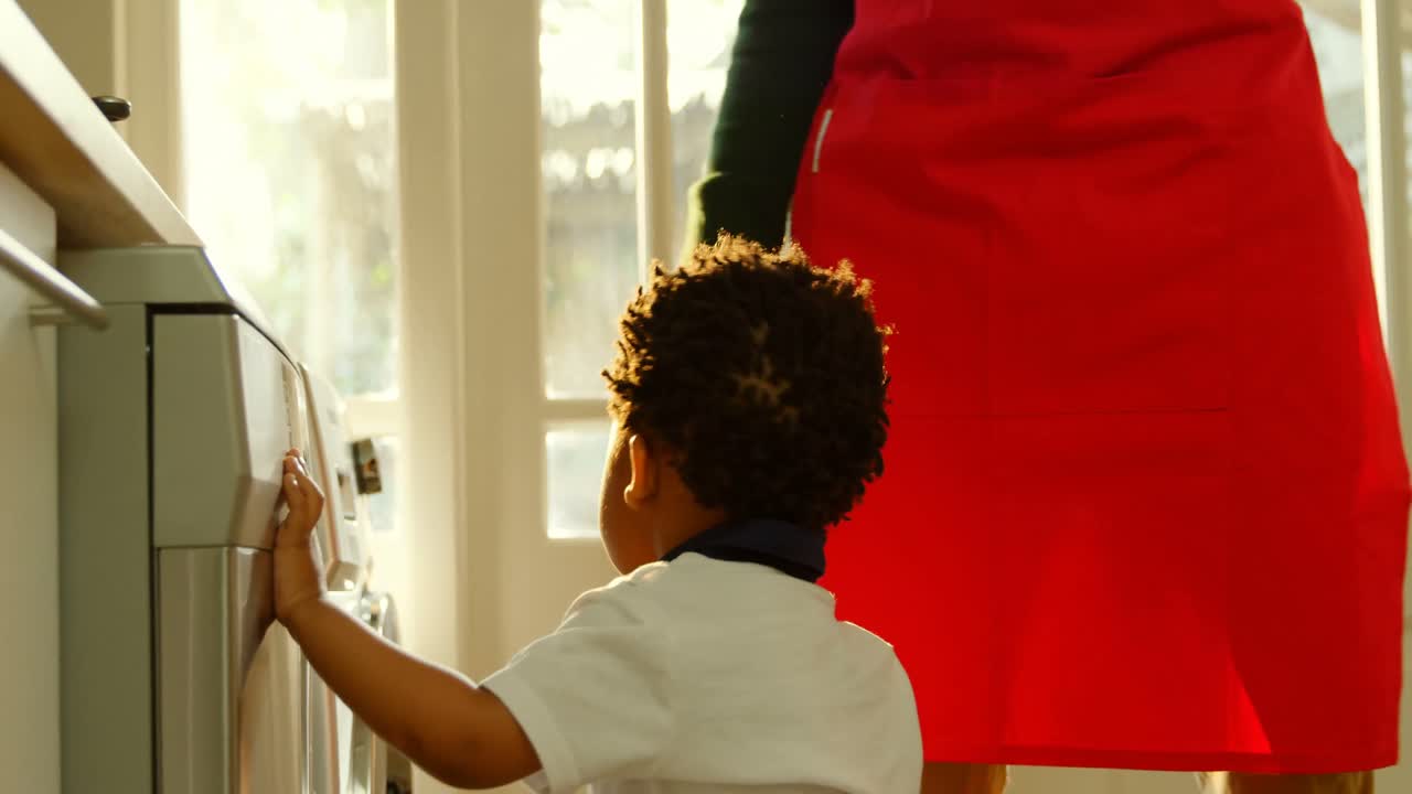 사이드 뷰 귀여운 작은 흑인 아들이 편안한 집 4k의 부 ⁇ 에서 세탁기에서 놀고