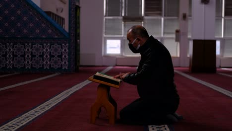 adult masked man reads the quran in mosque