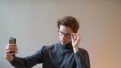 curly young guy taking a selfie on the phone with glasses