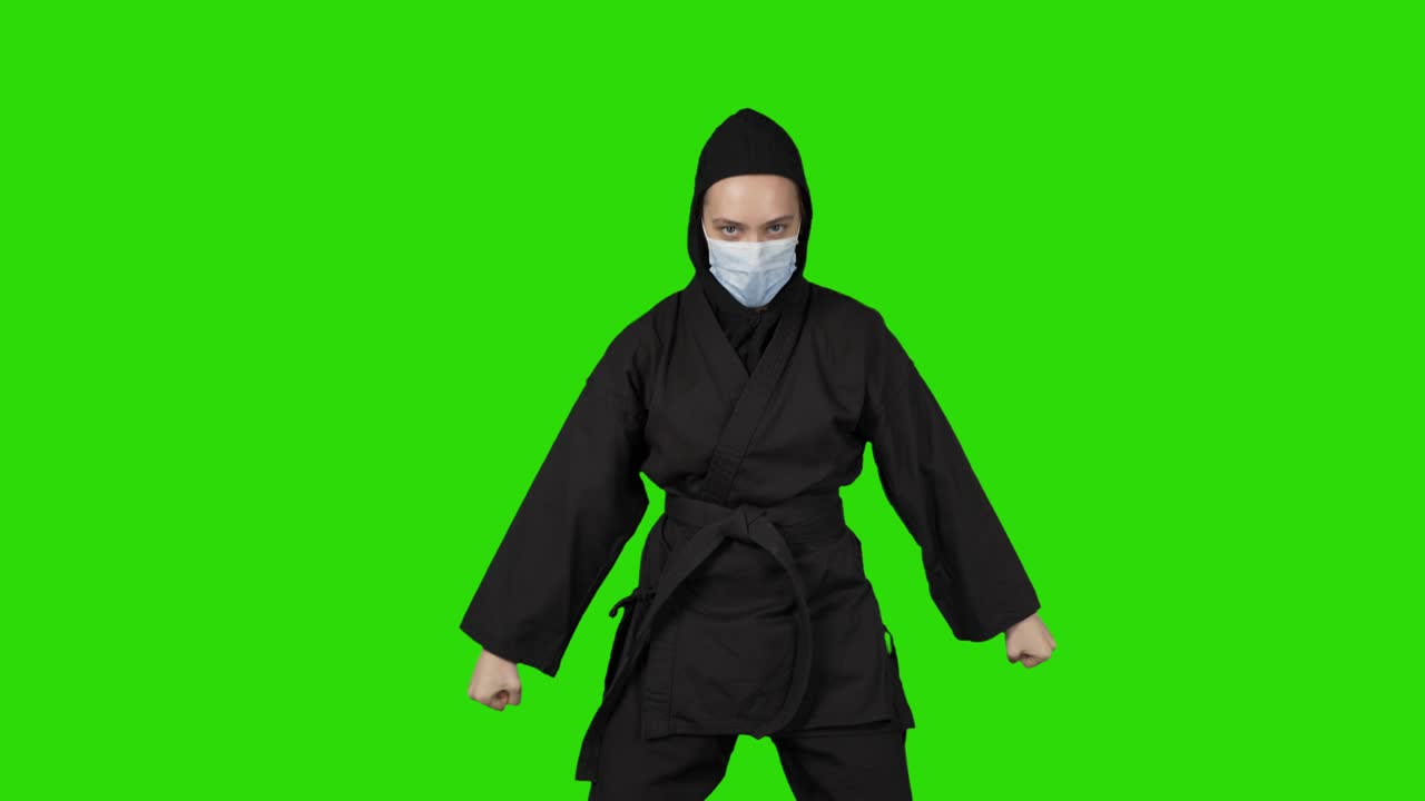video de una mujer en traje negro ninja en fondo verde