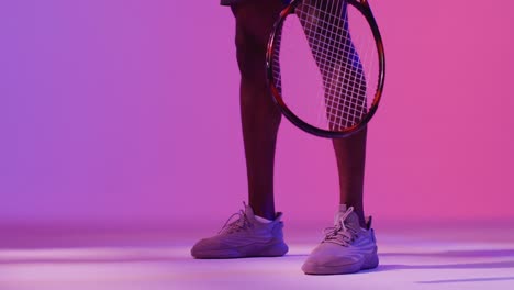 video of low section of african american male tennis player bouncing ball in neon pink lightning