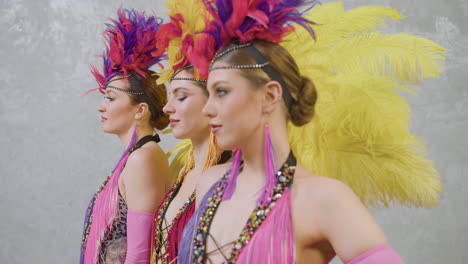 three young girls wearing feather gowns and dancing in a row