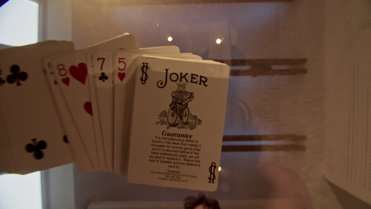 Fanned out playing cards featuring a Joker and number cards on display